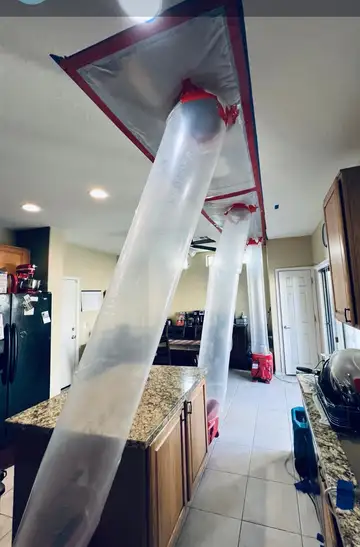 Plastic containment taped to a kitchen ceiling, with ducting tubes drying the wet ceiling cavity