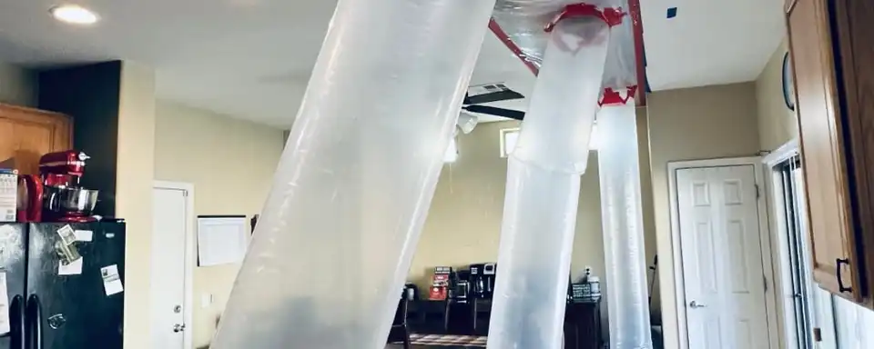 Plastic containment taped to a kitchen ceiling, with ducting tubes drying the wet ceiling cavity