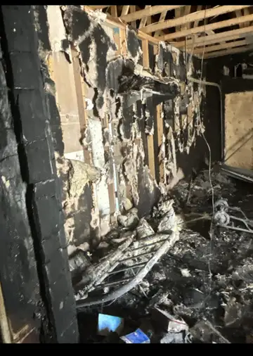 Charred wall framing and burned debris inside a fire-damaged house
