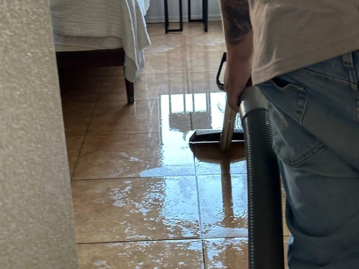 Fast Track technician extracting standing water from a tile floor in a Mesa home